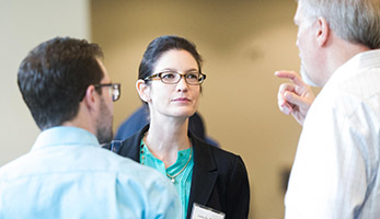 Woman at an event having conversation with two other people.